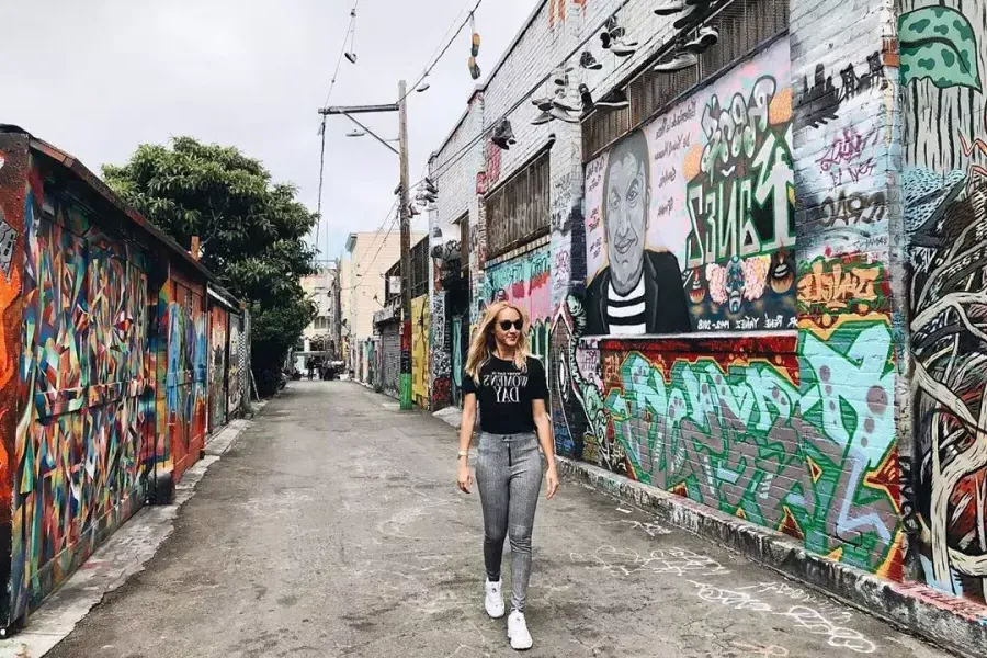 A woman walks through an alley in the Mission District that is covered with murals and artwork. 贝博体彩app，加利福尼亚.